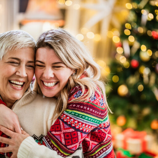 Woman hugging senior mother, helping her get in the holiday spirit.