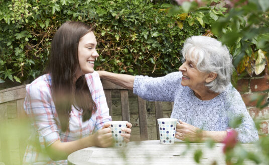 Young girl having coffee with senior woman demonstrating benefits of intergenerational programs