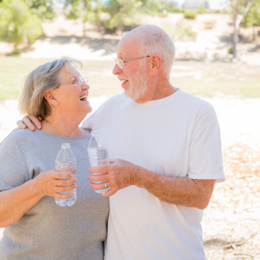 A senior couple staying hydrated in the summer, with their water bottles in-hand.