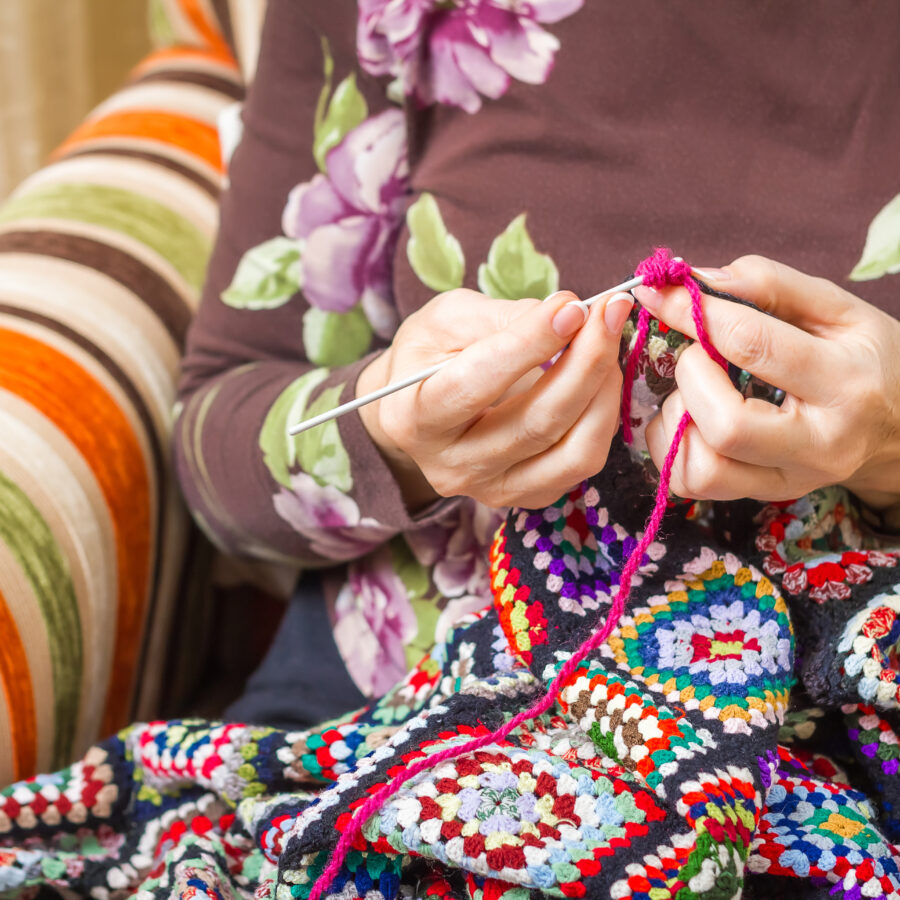 Senior woman plays with fidget blanket, which can be a tool to ease the nerves of seniors with dementia and anxiety.