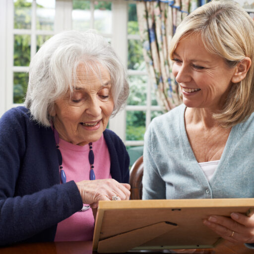 Senior woman looking at photos with her daughter. It can be confusing knowing when the right time to make the transition from Assisted Living to Memory Care, but knowing the signs of memory loss can help.