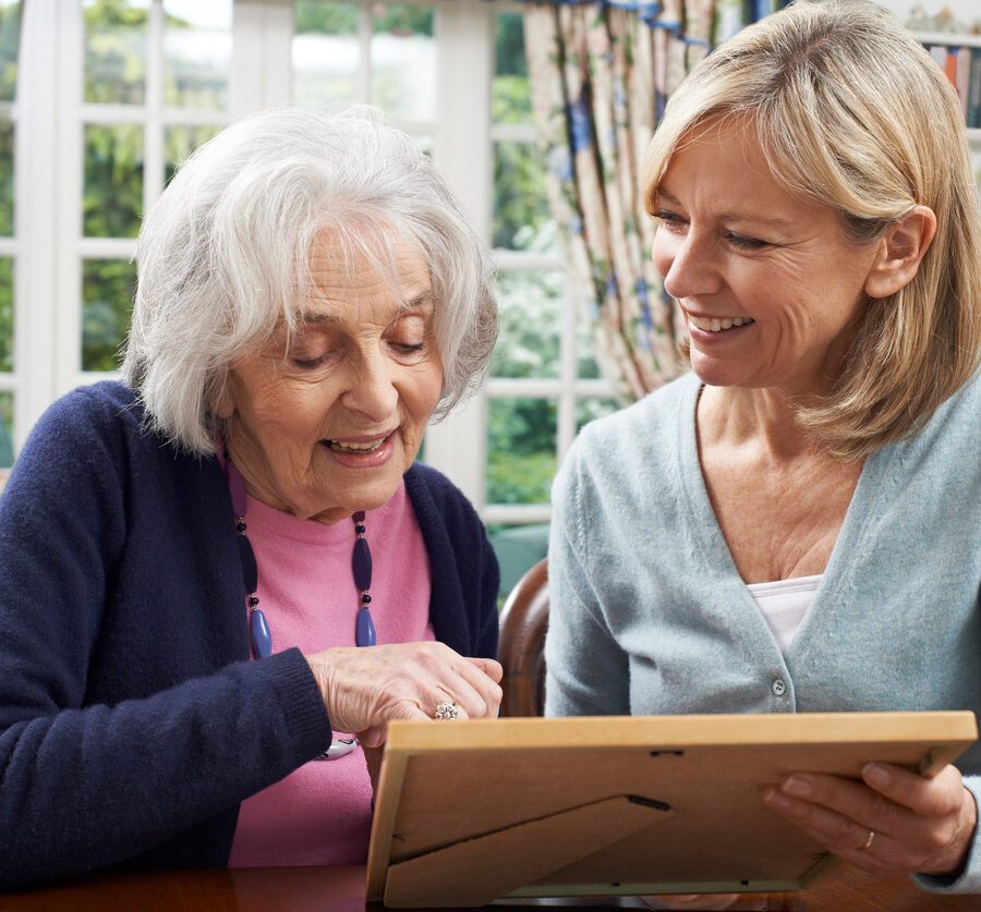 Senior woman looking at photos with her daughter. It can be confusing knowing when the right time to make the transition from Assisted Living to Memory Care, but knowing the signs of memory loss can help.
