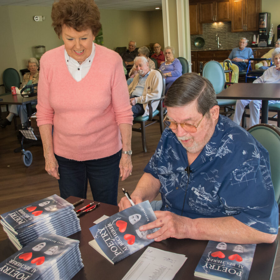 Al Becherer, a Bethesda Terrace resident, signs copies of his published book for his neighbors and fellow residents.