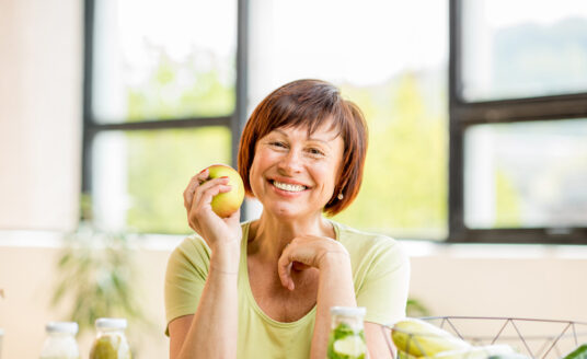 As you age, it's important to understand the importance of geriatric nutrition. Here, a senior woman eats an apple.