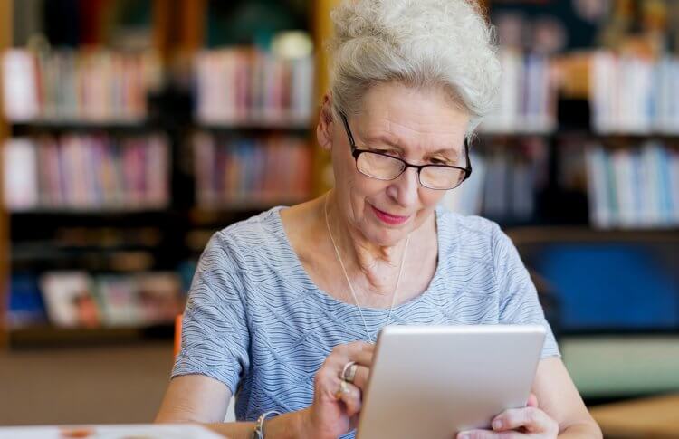 A senior using a tablet at the library.