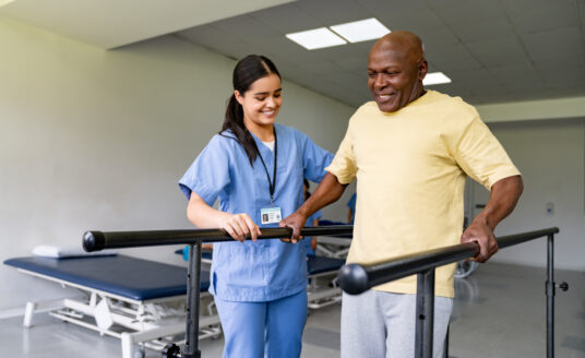 Senior experiencing rehabilitation benefits while being assisted by rehab specialist