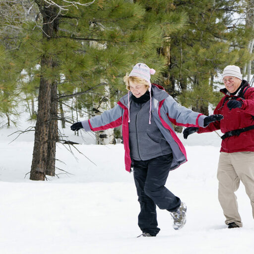 A senior couple takes a relaxing stroll in the snow. Taking time for yourself will help you avoid holiday stress.