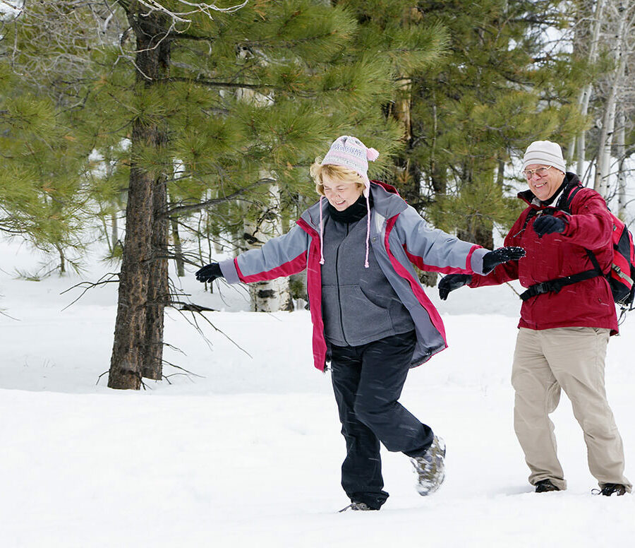 A senior couple takes a relaxing stroll in the snow. Taking time for yourself will help you avoid holiday stress.