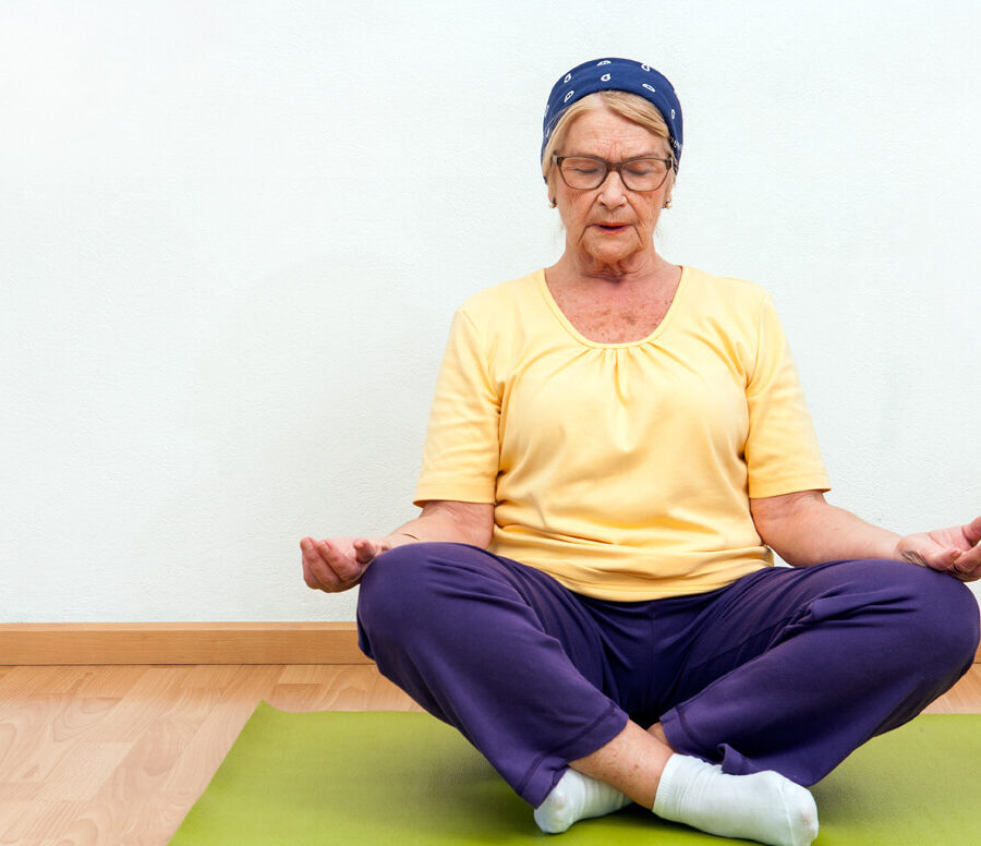 A senior woman meditates. The benefits of mindfulness meditation for seniors include stress relief and patience.