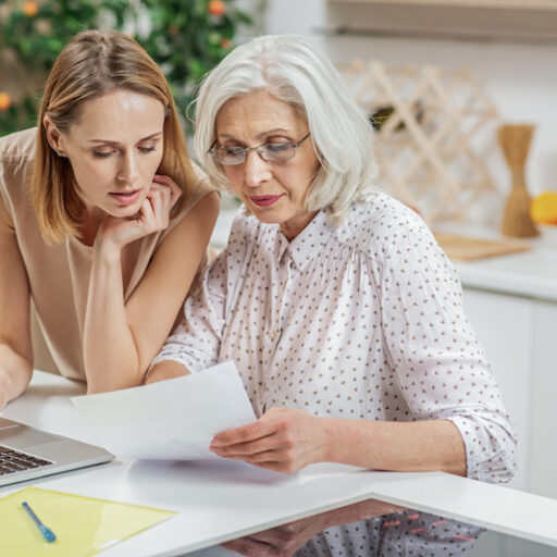 An adult woman and her senior mother look over materials when choosing an assisted living community.