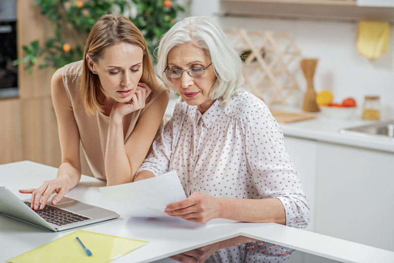 An adult woman and her senior mother look over materials when choosing an assisted living community.
