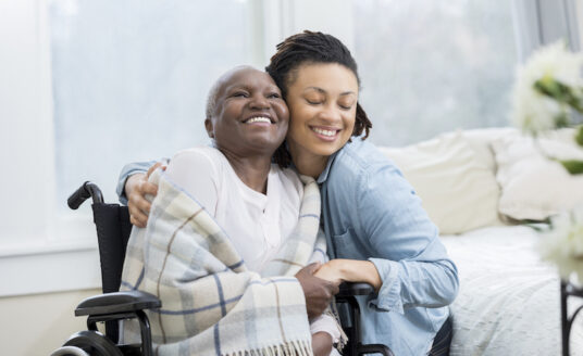 A woman hugs her senior mother to stay positive as a senior caregiver