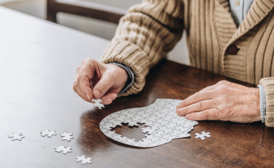 A senior man works on a puzzle, as he knows the importance of brain health