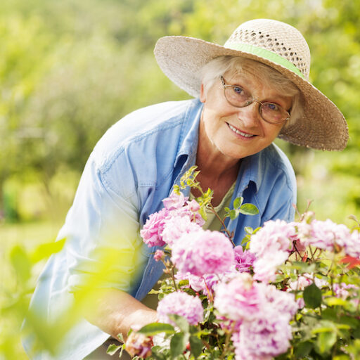 A senior woman plants flowers in her senior-friendly garden