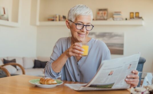 A senior woman enjoys the paper in her home, while she's aging in place.