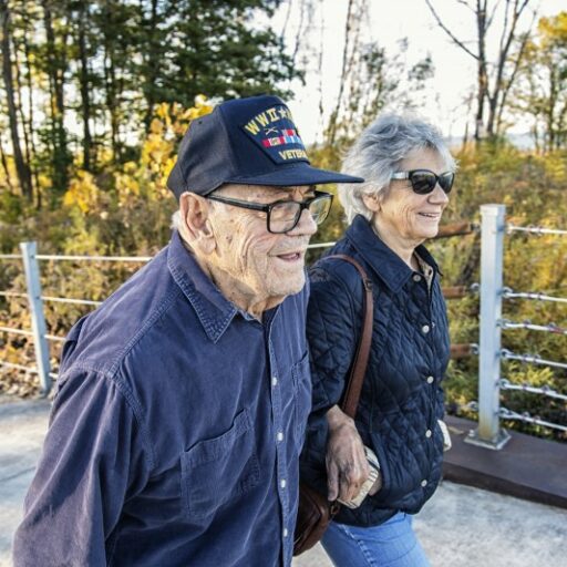 A senior Veteran and his wife walk along a trail at their senior living community.