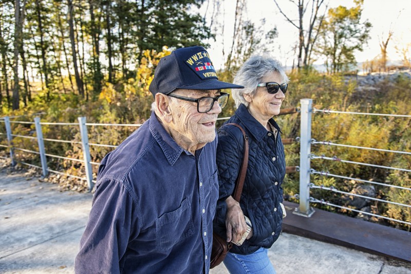 A senior Veteran and his wife walk along a trail at their senior living community.