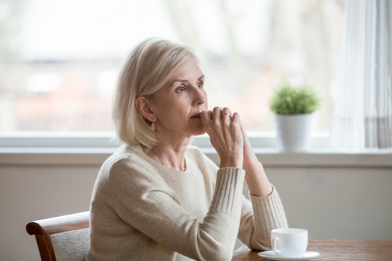 An adult woman contemplates her decision, as she may be feeling caregiver guilt after moving a parent into senior living.