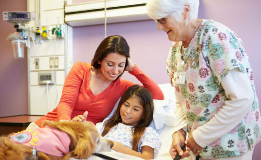 If you're looking for a meaningful retirement, try volunteering at a children's hospital. Here, a senior woman volunteers and visits with a child and her mother.