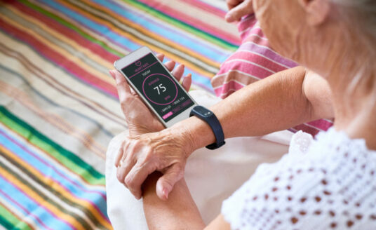 Technology improves quality of life for seniors. Here, a senior woman reviews her heart rate on her smart phone, which is connected to a Fitbit.