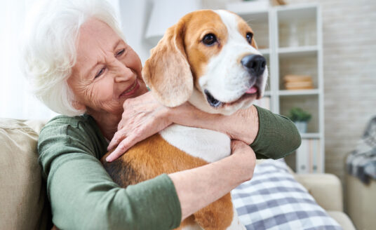 Senior woman hugging dog demonstrating positive benefits of seniors with pets