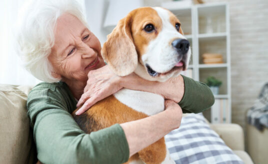 A senior woman hugs her dog. Keeping your pet as you age is proven to make us happier and healthier.