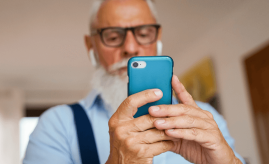 A senior man looks at hearing aid apps on his smart phone.