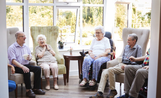 A group of seniors socialize at an independent living community, which offers safety and security to seniors living alone.
