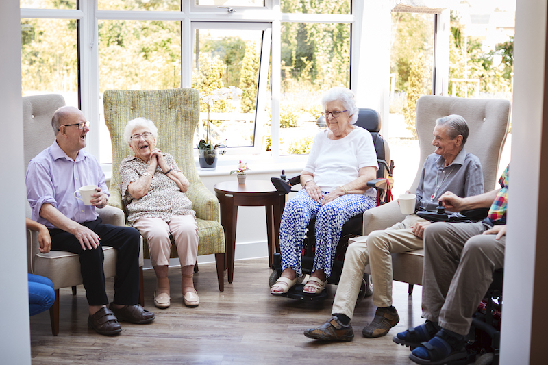 A group of seniors socialize at an independent living community, which offers safety and security to seniors living alone.