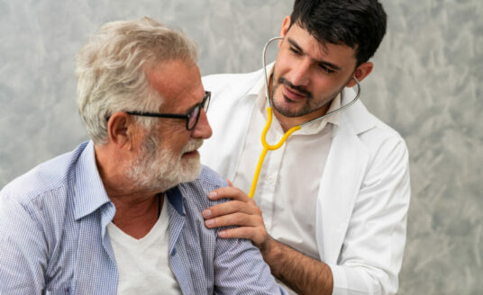 Doctor administering exam to prevent pneumonia in an elderly patient.