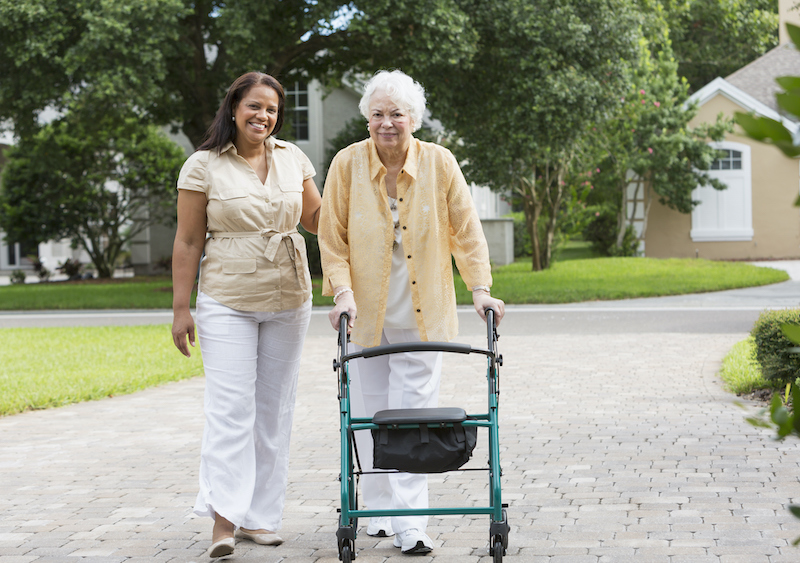 A woman walks with her senior mother, who recently moved home from Assisted Living