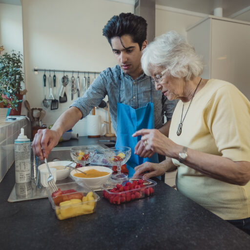 Young man preparing healthy meal with older adult.