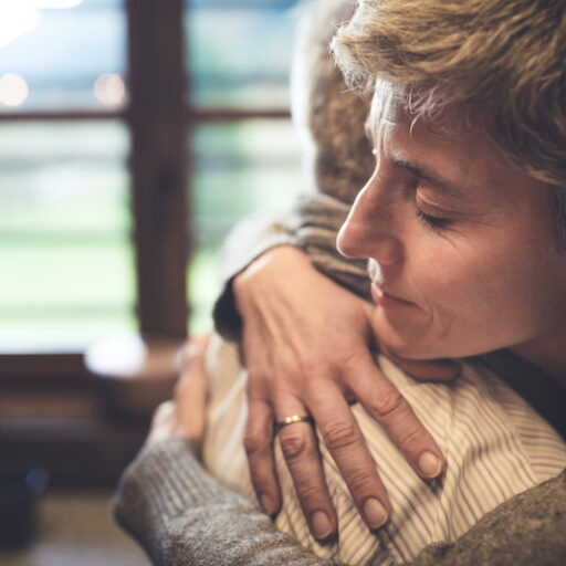 Adult child hugs elderly parent after receiving dementia diagnosis.