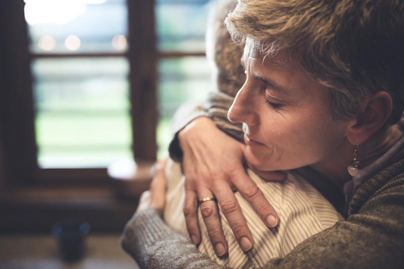 Adult child hugs elderly parent after receiving dementia diagnosis.