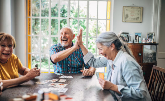 Group of older adults playing cards as a hobby..