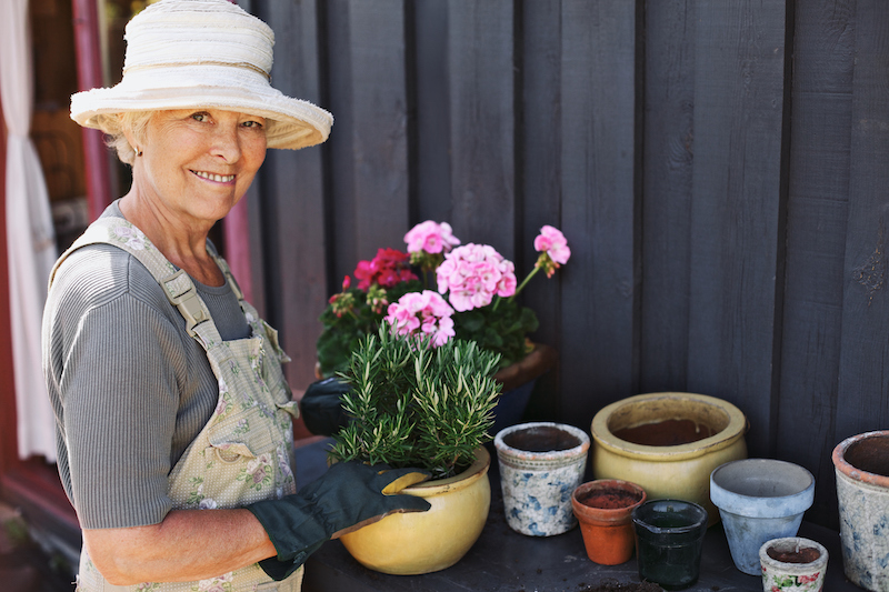 Active senior woman potting some plants after preparing to garden as a senior.