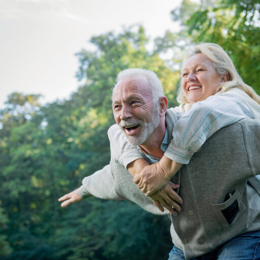 Happy, healthy senior couple smiling outdoors in nature with spring foliage | active senior living