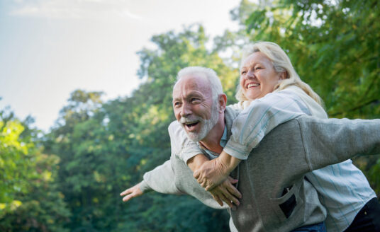 Happy, healthy senior couple smiling outdoors in nature will spring foliage.