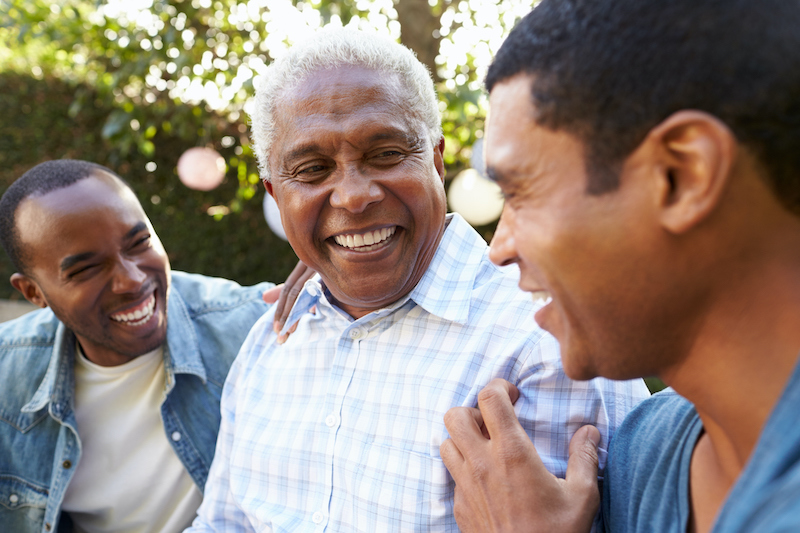 Senior man talking with his adult sons in garden, discussing Senior Stress Management