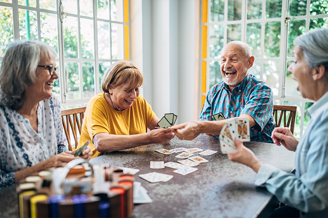 Men and women sitting at a table playing cards