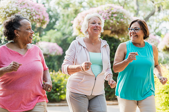 Three senior women speed walk together outside in the spring time