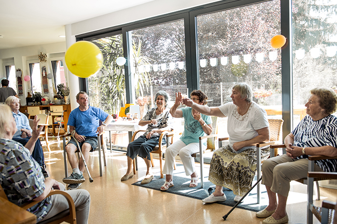 A group of seniors sit in a circle and play games together