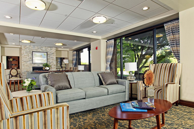 An image of the interior of Bethesda Dilworth, with a grey couch, striped arm chairs on either side, and a rug and coffee table.