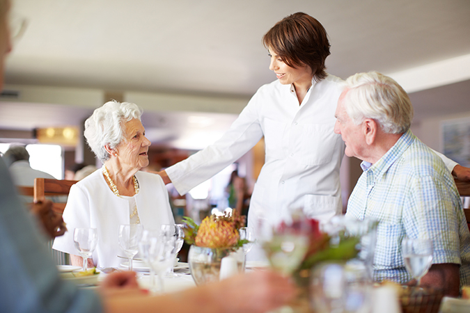 a senior man and woman are helped by a server at the dining hall of Barnes-Jewish Extended Care