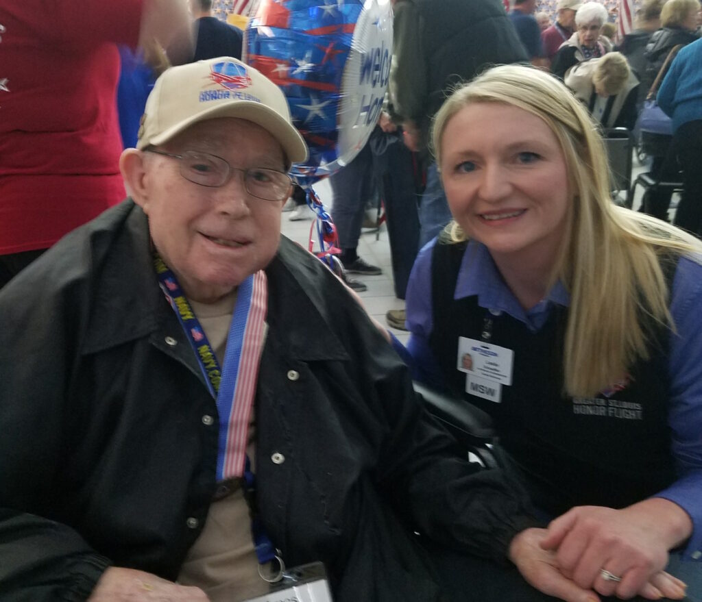 Amos Wilson, Bethesda Hospice Care patient and resident at Bethesda Dilworth, with Leslie Schaeffer, the Community Outreach Coordinator at Bethesda Hospice Care, at the Greater St. Louis Honor Flight\'s "Welcome Home" ceremony in March 2018.