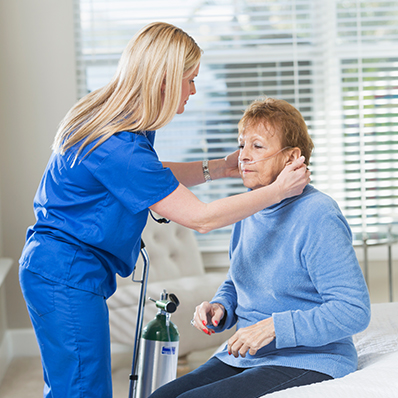 A senior woman receives help with her hearing aids from a hospice care professional