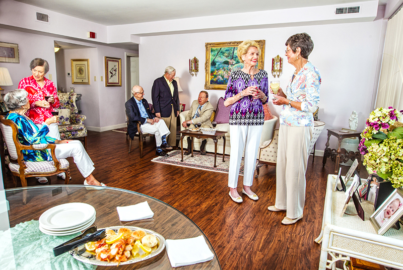 A group of senior women and men socialize in a nice living area