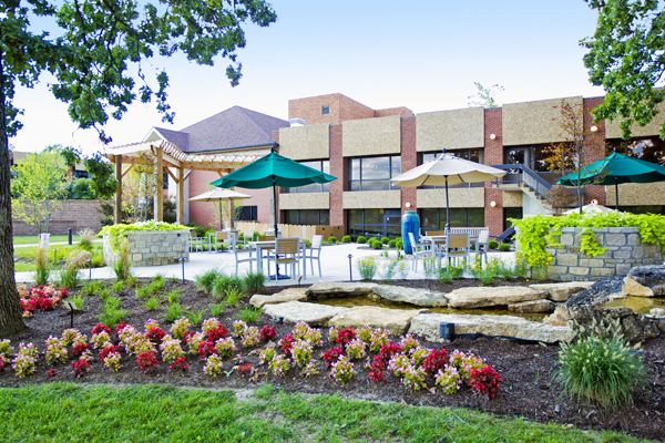 An image of the outside courtyard of Bethesda Dilworth, with tables and umbrellas and beautiful gardens