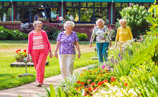 Four senior women enjoy a stroll in lush gardens at Bethesda Orchard