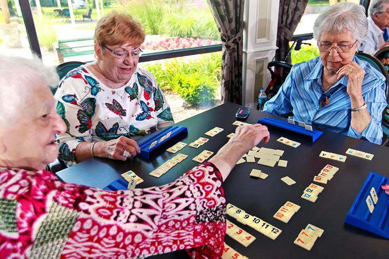 A group of three senior women enjoy a game of Rummikub at Bethesda Terrace